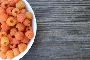 yellow raspberries in a bowl on the left, gray wooden table background copy space on the right. photo
