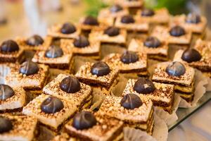 Delicious sweet cakes decorated with chocolate candy. Sweet festive buffet with desserts. Dessert table for the wedding. Fresh bakery. photo