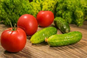 Fresh vegetables. Tomatoes and cucumbers on a wooden table photo