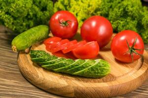 Fresh vegetables. Tomatoes and cucumbers on a wooden table photo