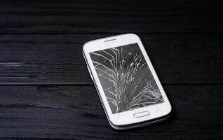 Smartphone with broken screen on dark background. Close-up. photo
