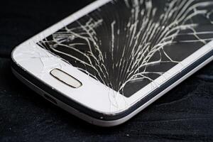 Smartphone with broken screen on dark background. Close-up. photo