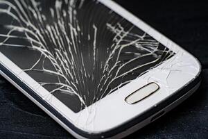 Smartphone with broken screen on dark background. Close-up. photo