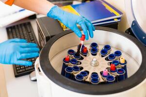 Doctor putting tubes of blood in centrifugal machine for testing and analyzing photo