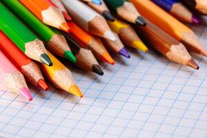 Color pencils on white background. Free space for text. Tools for drawing, education, school, creativity. Sheet of the notebook on the table. photo
