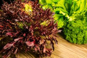 Leaves of lettuce and basil on a wooden background. Seasoning for the kitchen. Greenery. photo