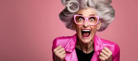 Excited Senior Woman with Pink Glasses and Gray Hair Celebrating Against Pink Background in Colorful, Fun, and Joyful Expression, Full of Life and Energy photo