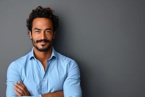 Confident Hispanic Man Standing Against Gray Background in Light Blue Shirt Smiling with Arms Crossed, Modern Casual Style for Profile or Business Use photo