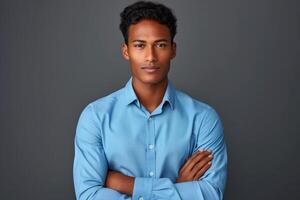 Confident Young Man in Blue Shirt Posing Against a Dark Background with Arms Crossed, Expressing Determination and Elegance in Studio Photography photo