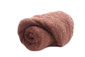 Rolled brown towel isolated on white background. Concept, clothes in daily life using. Towel for bathing, showering or spa massage. photo