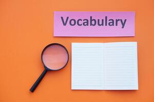Magnifying glass, paper notebook and vocabulary card. Concept. Education material.Teaching aid. Learning language. Find or search vocabulay in lesson. photo
