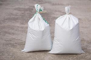 Two white polypropylene sack that contain full of agricultural grains, tied on the top with bamboo rope. Concept, reusable bag for contain crops, fertilizer or others. photo