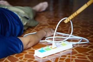 Using wooden stick is moving away the electric plug socket from the unconscious man who lay down on the floor. Concept, Electric Shock. Emergency basic rescue. First Aid photo