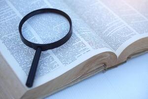 Megnifying glass on page of dictionary. Concept, Word searching. Education. photo