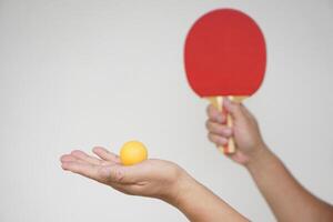 Selective focus on the orange ball on hand with serving table tennis racket. Concept, sport equipment. Exercise or workout tool. Competitive game sport. Playing Ping pong photo