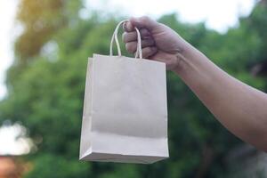 Hand hold brown paper bag. Concept, eco friendly packaging for containing things, can use many times. Reduce, Reuse, Recycle for conserve environment. Reduce plastic garbage campaign. photo
