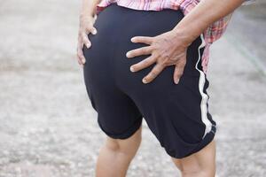 Close up elderly woman hands touching, holding buttock. Concept, health care and health problems. Suffering from bottom pain. Henorrhoid. Body weak and tired. photo