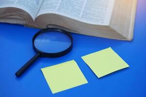 Magnifying glass, yellow paper and book. Concept, education. Searching answers or knowledge from reading books. Study and research. Inquiry-Based Learning strategy. Discovery from read textbooks. photo