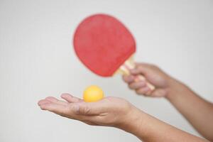 Selective focus on the orange ball on hand with serving table tennis racket. Concept, sport equipment. Exercise or workout tool. Competitive game sport. Playing Ping pong photo