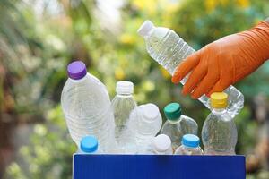 Hand holds used plastic bottle to put in junk bin for recycling. Concept, sorting garbage campaign before throw away for reuse or recycle. Environment conservation. Eco friendly activity. photo
