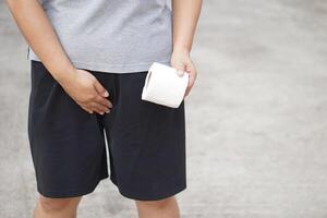Close up man holds tissue paper roll and crotch , want to go to toilet from cystitis symptom or urinary tract infection. Concept, illness,health problem and health care. photo