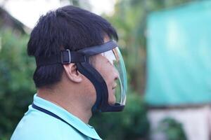 Asian man wears protective safety face shield. Concept, tool, equipment use for wearing with face to protect from dust, germ spreading or others into face. Work Secured helmet shield. photo