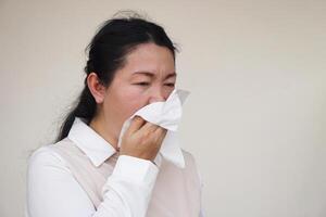 Asian woman hold white tissue paper to cover her mouth or clean runny nose with snot from cold or allergy symptoms. Concept, Health problems. Cover mouth when cough or sneeze to stop spreading of germ photo