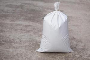 White polypropylene sack that contain full of agricultural grains, tied on the top with bamboo rope. Concept, reusable bag for contain crops, fertilizer or others. photo
