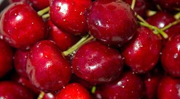 A bunch of red cherries are sitting on a table. The cherries are shiny and wet, and they are arranged in a pile photo