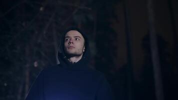 A young guy returns home through the forest. A man with a backpack walks through a dark night forest. video