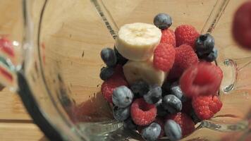 Adding raspberries, blueberries and bananas to a blender to make a smoothie. The smoothie ingredients are ready to be blended. video