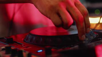 Close-up view of mixing console when DJ choosing a track, rotating the jogwheel. Musician playing music on the controller during a party with color illumination video