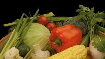 A wooden crate filled with fresh vegetables. The crate contains a variety of colorful produce, including tomatoes, green peppers, yellow peppers, cabbage, cucumbers, scallions, and corn. video