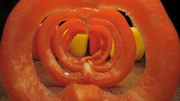 Red and yellow bell peppers on a wooden table. The camera moves through the pepper cut into rings. video