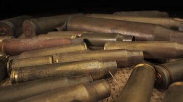 A close-up view of a collection of spent brass casings on a Burlap Surface. The casings are of various lengths and have been used, leaving them with a dull, worn appearance. video