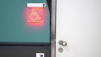 The door to the restroom is accessible and has an illuminated handicap sign for easy recognition video