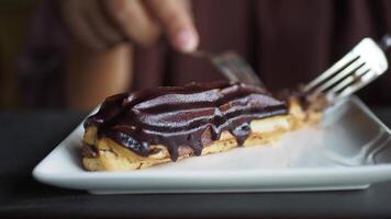 nel il Immagine, qualcuno è utilizzando un' forchetta e coltello per fetta un' cioccolato pasticcino su un' piatto video