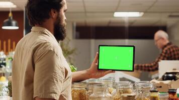 Customer using isolated screen tablet in zero waste supermarket to check ingredients for healthy recipe. Client in local grocery shop uses mockup device while shopping for pantry staples photo