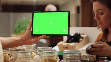 Man uses landscape mockup tablet in sustainable zero waste supermarket to check ingredients for healthy recipe. Vegan client in sustainable local shop with chroma key device shops for pantry staples photo