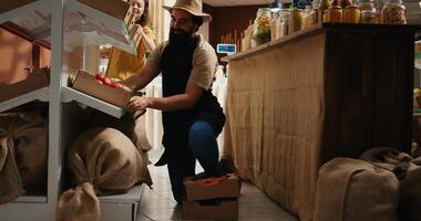 Storekeeper arriving in eco friendly supermarket with freshly harvested organic food stock. Trader restocking local neighborhood grocery shop with chemicals free vegetables while chatting with client photo