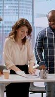Vertical Professional clients and their real estate agent evaluating blueprints for the high class modern space, discussing leasing contract terms before signing. Startup business development. Camera A. video