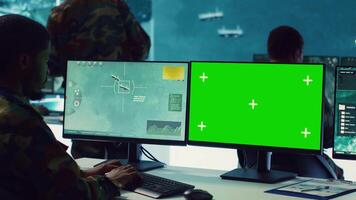 Private monitors national guard activity with military CCTV satellite system, working with a greenscreen display on pc in command center. IT reconnaissance operator tracking ships. Camera A. video