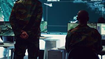 Sergeant major of the army handling a secret service operation by gathering intelligence from field troops and satellite CCTV imagery. Conducting a reconnaissance mission in command post. Camera A. video