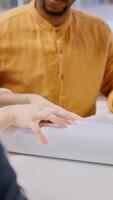 Vertical Real estate brokers meeting with client to reach an agreement for property leasing contract, evaluating urban property blueprints and negotiating terms for a high class corporate building. Camera A. video