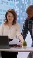 Vertical Business professionals and a real estate agent engage in a planning session, discussing the layout and design of a new office space based on detailed blueprints. Property investment. Camera A. video