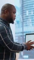 Vertical Real estate broker and client negotiating a leasing contract for a high class modern office space, evaluating blueprints on tablet during office tour. Property investment opportunity. Camera B. video