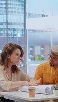 Vertical During an office tour, professional clients and realtor review blueprints and discuss investment strategy for modern workspace development. Strategizes layout of new urban office space. Camera B. video