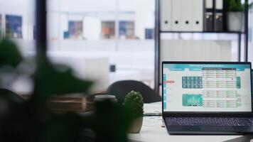 Laptop device on corporate office desk in empty workspace showing volatile stock exchange prices going up and down. Brokerage firm with forex trading platforms indexes on device screen video