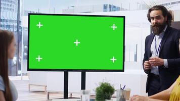 Financial adviser presents market analytics on green screen display to clients, teaching them how to build portfolio. Broker showing stock exchange charts on mockup device to family, camera B video