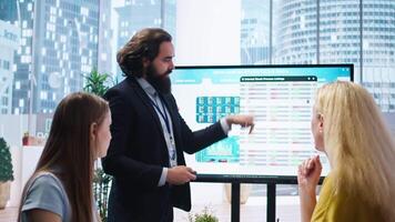 Financial advisor presents detailed stock market analysis to clients on big screen, helping them make informed investment decisions. Broker in office providing family with financial analysis, camera A video